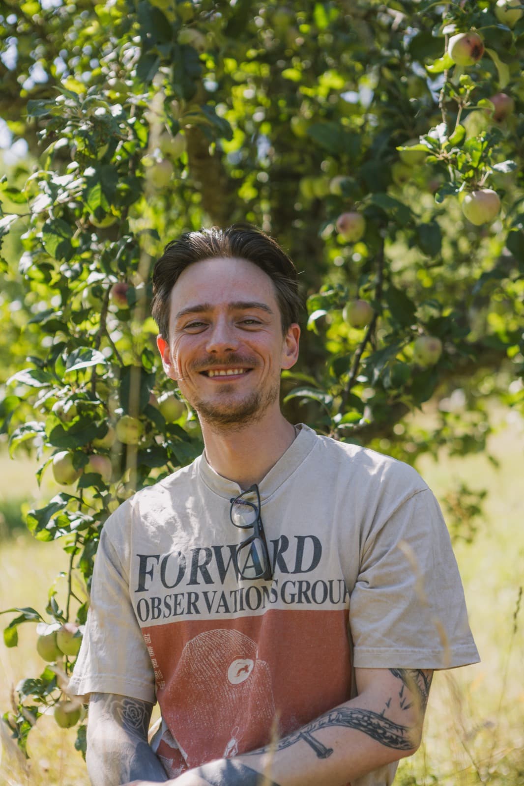 Samuel Schäck lachend vor einem Apfelbaum
