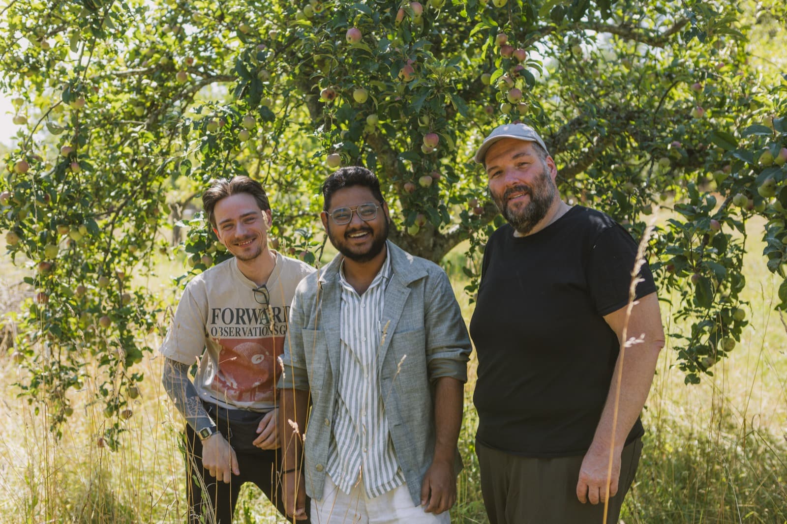 Samuel Schäck mit Shashank und einem weiteren Teammitglied unter einem Apfelbaum